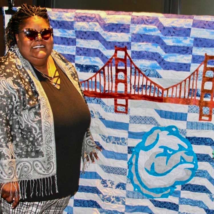 woman standing in front of blue and white quilt with a bridge