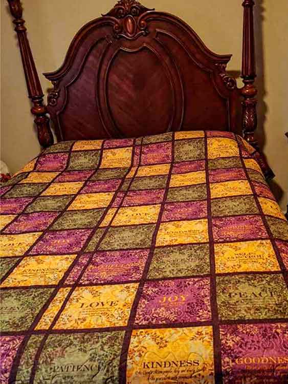 purple, yellow, and green block quilt draped over bed