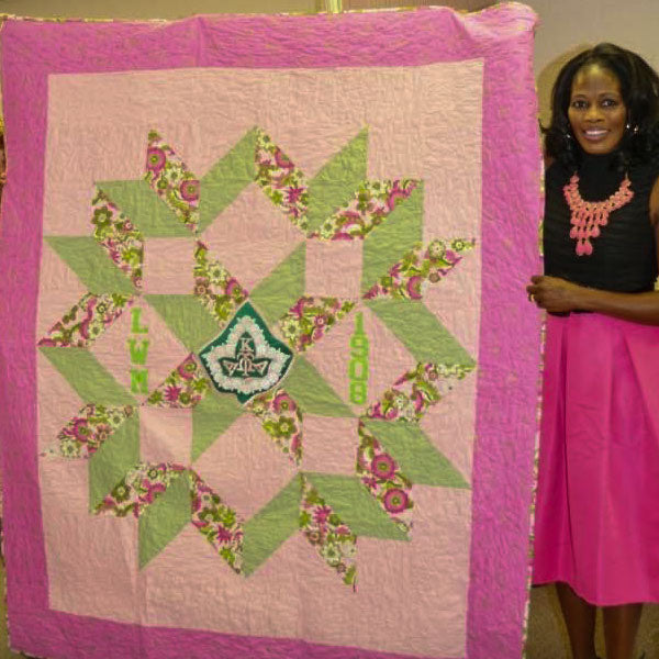 Woman holding up pink and green quilt