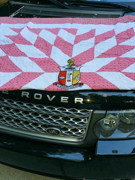 pink and white pointed block quilt draped over range rover hood